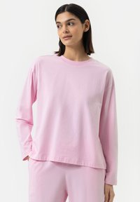 Lange mouwen roze katoenen top met een ronde halslijn en een ontspannen pasvorm. Gladde textuur zonder zichtbare patronen of versieringen.