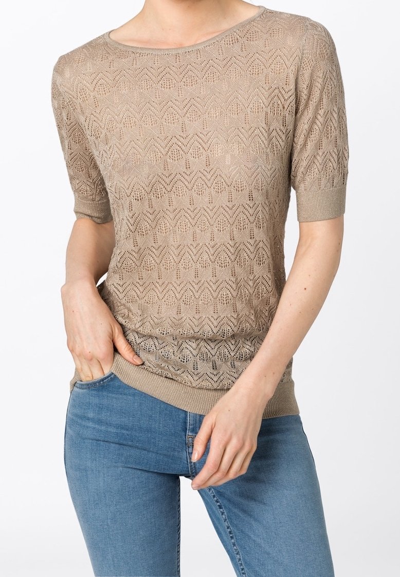Top de punto beige de manga corta con un patrón geométrico, escote redondo y dobladillo acanalado. Combinado con jeans de mezclilla azul.