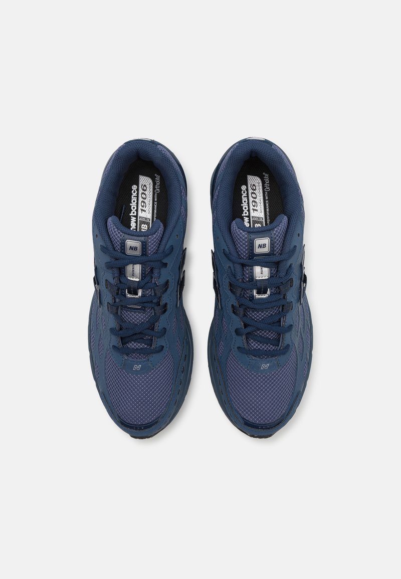 Baskets de sport bleu marine avec des empiècements en maille et en synthétique, dotées de lacets solides, d'un col rembourré et d'accents du logo "NB" sur la languette.