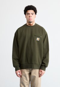 Sudadera verde oliva de tejido suave, con escote redondo, puños acanalados y un pequeño bolsillo con logotipo en el pecho.