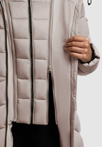 Lahka pufasta jakna v mehkobezgi z vzorcem kvačkanja. Ima dvojne zippers in gladko notranjo oblogo. Poudarjena z črnim kovinskim okovjem.