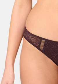 Lila spets-trosa med blommönster, släta kanter och en semi-transparent meshinsats baktill, med en låg midjdesign.