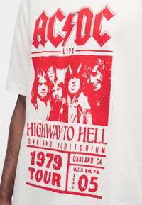 T-shirt blanc avec logo rouge du groupe AC/DC, photo de groupe et texte faisant référence à la tournée "Highway to Hell" de 1979 à l'Auditorium d'Oakland, le 5 septembre.