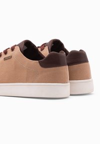 Béžové plátěné boty s hnědými koženými detaily, kulatá špička a bílá gumová podrážka. Obsahují vínové tkaničky a nenápadný logo detail na boku.