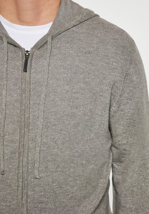 Grauer Reißverschluss-Hoodie aus strukturiertem Stoff, ausgestattet mit einer Kapuze, Kordeln und einem Metallreißverschluss an der Vorderseite.