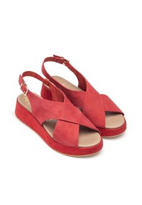 Red suede wedge sandals with a cross strap design, open heel, and a textured footbed. Features a metallic buckle for adjustment.