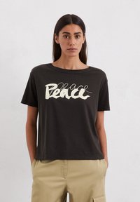 Schwarzes Baumwoll-T-Shirt mit lockerer Passform und Rundhalsausschnitt, mit dem Aufdruck "Peace" in cremfärbiger, geschwungener Schrift auf der Vorderseite.