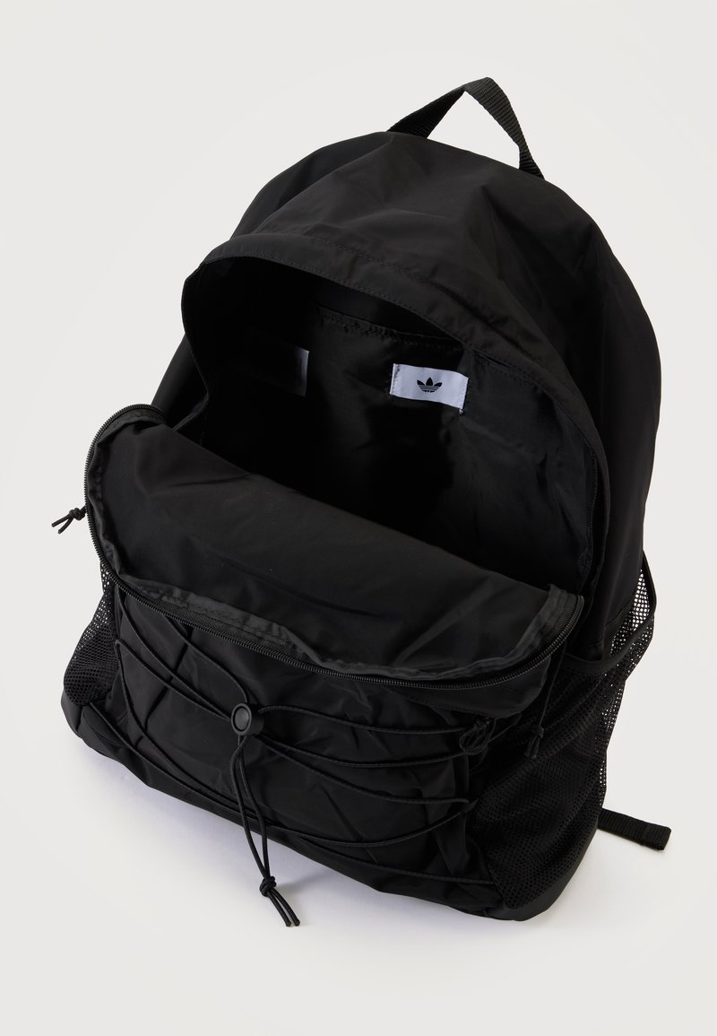 Black Adidas backpack with open main compartment, front zipper pocket with elastic cord, and side mesh pockets on white background.