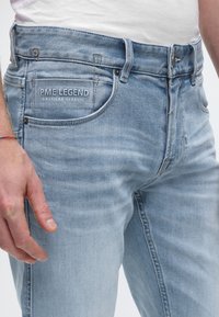 Lichtblauwe denim jeans met een vervaagde finish, voorzien van een zichtbaar merklogo op het achterzakje en standaard lussen voor een riem.