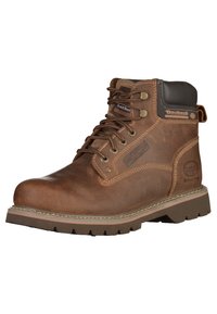 Bota de trabajo de cuero marrón con punta redonda, sistema de cordones, collar acolchado y suela de goma resistente. Presenta un detalle del logo en el costado.