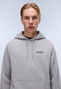 Grijze hoodie met een aantrekkoord, voering van een voorzak en een klein merklogo op de borst. Kenmerkt zich door een zachte, gestructureerde stof.