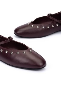 Ballerine in pelle bordeaux scuro con borchie argentate rotonde attorno all'apertura e una sottile fascia sulla parte superiore.
