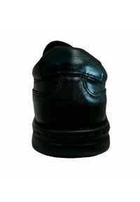 Zapato de cuero negro con punta redondeada, costuras detalladas y un tacón texturizado. Suela plana de goma para mayor estabilidad. Diseño minimalista.