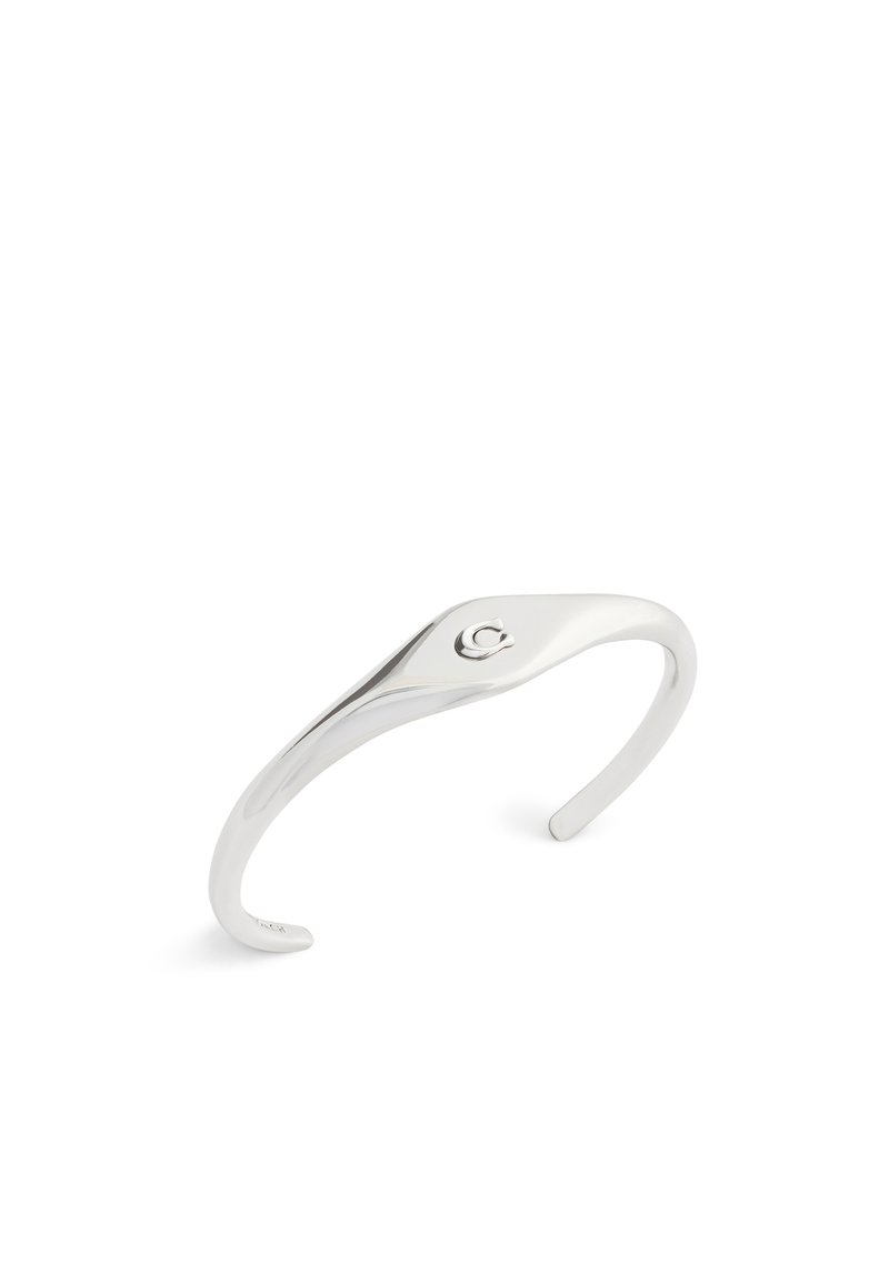 Bracelet en cuivre argenté avec un design élégant et courbé ; texture lisse ; présente un petit accent de logo à une extrémité. Forme ouverte pour un ajustement réglable.