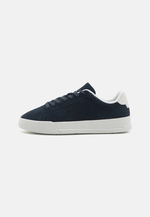 Sneaker in suede blu navy con suola in gomma bianca, punta arrotondata e design con lacci. Presenta un tallone a contrasto e un branding minimalista sul lato.