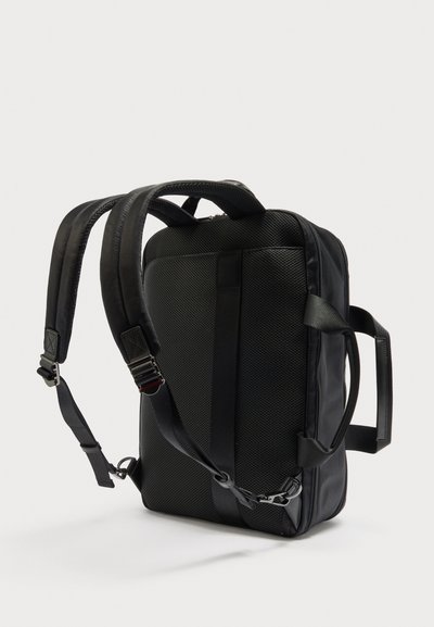 Μαύρο ορθογώνιο σακίδιο με επενδεδυμένους ρυθμιζόμενους ιμάντες, πλέγμα στην πίσω πλευρά και πλευρική λαβή σε ανοιχτό φόντο.