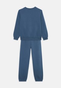 Conjunto de sudadera y pantalones azules hecho de una tela suave. El diseño presenta puños y cinturilla acanalados con un ajuste relajado.
