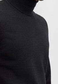Czarny sweter z golfem wykonany z delikatnej dzianiny, o dopasowanym kroju i gładkiej fakturze. Bez widocznych wzorów ani ozdób.