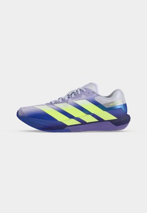 Chaussure de sport basse violette et bleue avec des bandes Adidas jaune néon, des lacets blancs et un col de talon gris clair sur fond blanc.