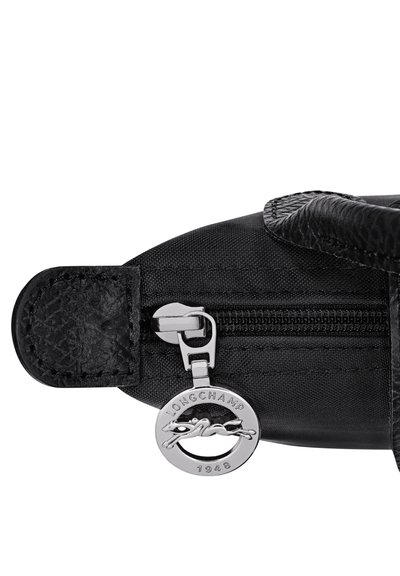 Black fabric zipper with round silver Longchamp logo pull tab showing a horse and rider and the year 1948 on a bag corner.