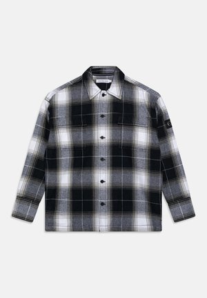 Czarna, biała i szara koszula w kratę z długim rękawem, zapinana na guziki, z kołnierzem i kieszeniami na piersi, z naszywką Calvin Klein Jeans na kołnierzu i naszywką na rękawie.