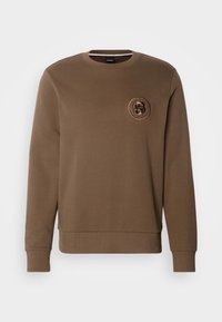 Sweat-shirt marron à manches longues avec col rond, doté d’un petit logo circulaire texturé avec la lettre « S » sur la poitrine gauche.