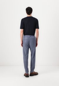 T-shirt à manches courtes navy associé à un pantalon léger bleu sur mesure avec une ceinture élastique et deux poches arrière, vu de dos.