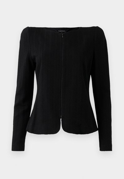 Chaqueta negra de manga larga con textura, con cremallera frontal y dobladillo ligeramente acampanado, presentada sobre un fondo blanco.