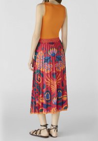 Jupe évasée de longueur genou avec des motifs floraux et abstraits colorés, à base rouge vif et large ceinture élastique marquée "Tropical."