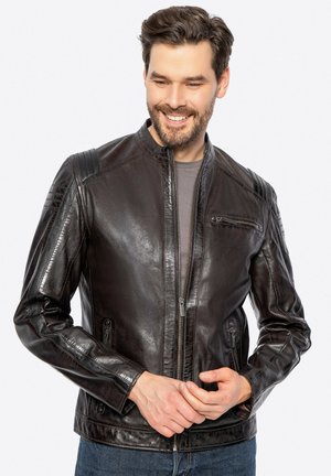 Chaqueta de motocicleta de cuero negro con cuello alto, cierre frontal de cremallera y múltiples bolsillos. Presenta acentos texturizados en los hombros y un acabado suave.