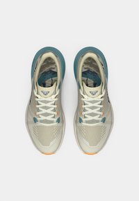 Ελαφριά αθλητικά παπούτσια τρεξίματος σε κρέμ απόχρωση με τιρκουάζ λεπτομέρειες, διχτυωτό επάνω μέρος για αναπνοή, παχύ πάτο και έντονα πορτοκαλί στοιχεία.