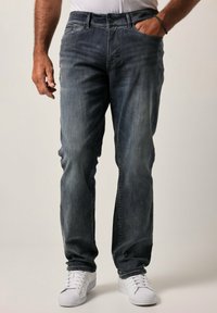 Jeans de mezclilla gris con un corte relajado, con un ligero desgaste, diseño de cinco bolsillos y combinados con zapatillas blancas.