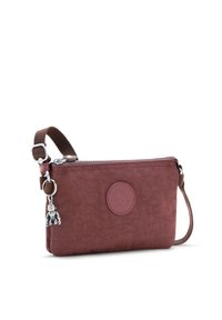 Bolsa compacta de cremallera color burdeos hecha de tela texturizada, con un parche de logo redondo y un charm plateado de llavero con una figura. Incluye correa marrón.