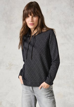 Pull-over noir en hoodie avec un motif en losanges, capuche avec cordon, manches longues et poche avant, associé à un jean gris clair.