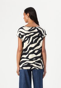 Camiseta de estampado de cebra en negro y crema, con mangas cortas y un corte relajado, fabricada en suave tejido de algodón y con un escote amplio.