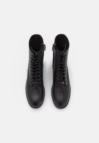 Black leather ankle boots with a textured design, featuring laces, a side zipper, and a smooth toe. Detailed metal hardware accent.
