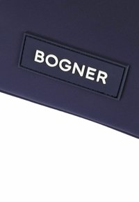 Granatowa torba z tkaniny o teksturowym wykończeniu, z białym wytłoczonym logo "BOGNER" na prostokątnej metce. Prosty design, minimalne akcenty.