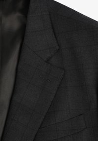 Blazer gris oscuro hecho de una tela texturizada, con un sutil patrón de cuadros, diseño de un solo pecho y bolsillos en los laterales. Forro interior visible.