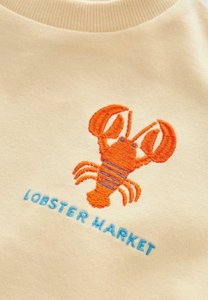 Beige sweatshirt med en orange broderet hummer med blå striber og teksten "LOBSTER MARKET" nedenfor i en matchende blå skrifttype.