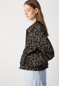 Zwarte en olijfgroene luipaardprint jas met een ritssluiting aan de voorkant, oversized kraag en zijzakken; heeft een relaxte pasvorm en een gladde textuur.