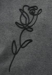 Tecido cinza escuro com um contorno preto bordado de uma rosa com caule e três folhas.