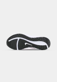 Semelle en caoutchouc noire et blanche d'une chaussure de course Nike avec un motif antidérapant texturé et le logo Nike Swoosh visible au centre.