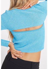 Top corto a coste blu con maniche lunghe e dettaglio sulla schiena aperta, che mette in mostra un motivo texture e una silhouette aderente.