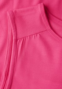 Canotta atletica rosa realizzata in tessuto liscio e elasticizzato. Presenta un colletto a forma di scollatura rotonda, spalline larghe e un dettaglio con cucitura arricciata sul lato.