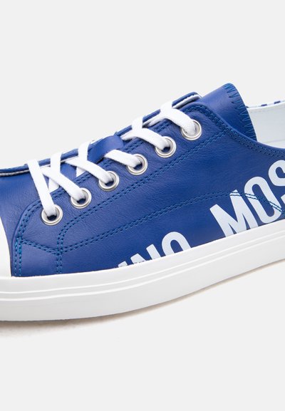 Μπλε δερμάτινο αθλητικό παπούτσι με λευκά κορδόνια, μεταλλικούς οφθαλμούς, λευκή ελαστική σόλα και μερικώς ορατό μεγάλο λευκό κείμενο στο πλάι.