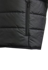 Svart puffervest med quiltet design og glidelås på siden. Laget av et glatt, matt materiale med avrundet kant og flate sømmer.