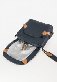 Dark blue crossbody bag with tan leather accents, front zipper pocket, open main compartment, and adjustable black strap on white background.