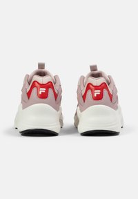Une paire de baskets roses et blanches avec des accents rouges et le logo de la marque sur le talon, montrant la vue arrière sur un fond blanc uni.