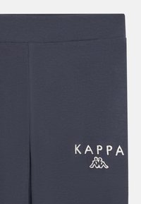 Temno modre Kappa leggingse iz mehkega in elastičnega materiala. Imajo belo vezeno logo na levi strani in gladek pas.