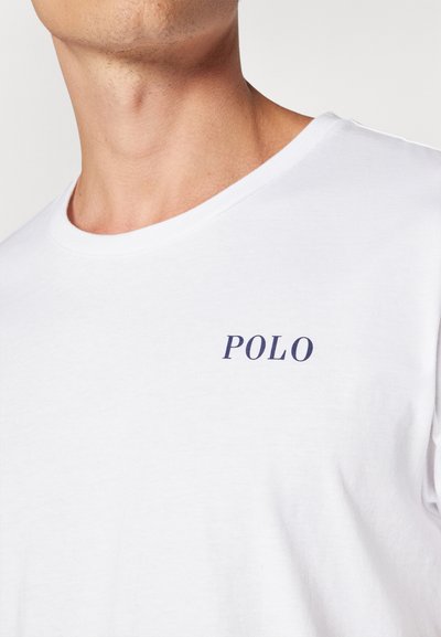 Biela bavlnená tričko s okrúhlym výstrihom a námorníckym logom "POLO" na ľavej strane hrude. Hladká textúra, klasický strih.